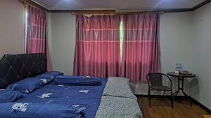 a bedroom with a bed and a table and a window at Ban Roi Pah in Ban Khlong Si