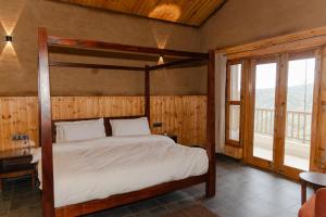 The Meemos Cafe And Cottages في تشاكراتا: غرفة نوم بسرير مظلة في غرفة بشرفة