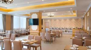 ein Restaurant mit Tischen und Stühlen und einem Fernseher in der Unterkunft Vienna Hotel Guangdong Qingyuan Wanda Plaza Xincheng Beijiang in Qingyuan