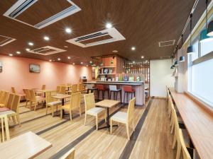 a restaurant with wooden tables and chairs and a bar at Comfort Hotel Kumamoto Shinshigai in Kumamoto