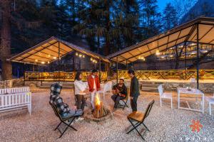 Zostel Kasol, Main Market في كاسول: مجموعة من الناس يجلسون حول النار أمام المبنى