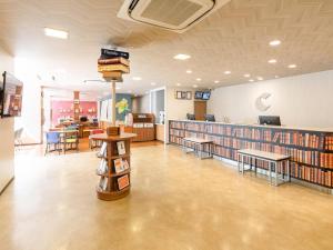 a library with shelves of books and tables and chairs at Comfort Hotel Maebashi in Maebashi
