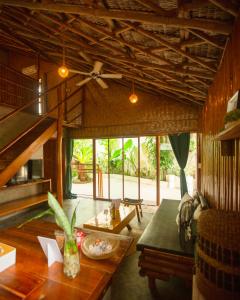 ein Wohnzimmer mit einem Deckenventilator und einem Tisch in der Unterkunft Happiness Native Villa in El Nido
