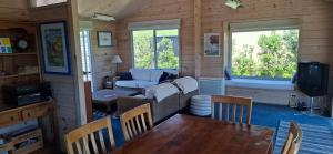 een woonkamer met een bank, een tafel en stoelen bij A Waihi Beach Getaway in Waihi Beach