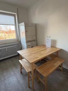 Altstadtperle Ettlingen mit Smart TV und WLAN في إيتلينغن: طاولة خشبية ومقعد في مطبخ مع ثلاجة +5 صور