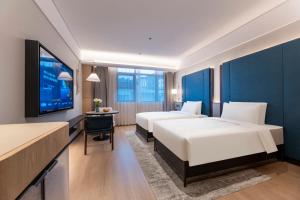 ein Hotelzimmer mit zwei Betten und einem Flachbildfernseher in der Unterkunft Changzhou Railway Station Qingguoxiang Manxin Hotel in Changzhou