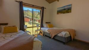 a bedroom with two beds and a large window at Wonderland Cottages in Halls Gap