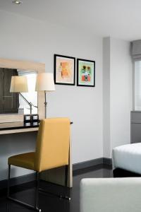 a bedroom with a yellow chair and a bed at Garner Hotel Pattaya Central by IHG in Pattaya