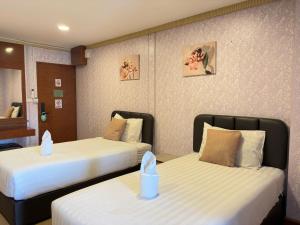 two beds in a hotel room with twin beds at OYO 75446 Travis Inthamara 49 in Bangkok