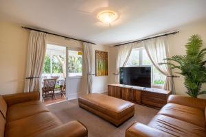 a living room with a couch and a tv at 1 Mustique River Club in Plettenberg Bay