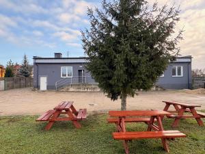 two picnic tables and a tree in front of a house at Golenicka Przystań Golenice 73a in Golenice
