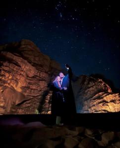two people sitting on a rock under a starry sky at stars magic camp in Wadi Rum