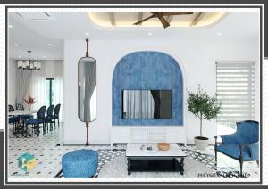 a living room with blue chairs and a tv at Villa Malibu Tropicana , Nova Hồ Tràm in Ấp Thanh Bình