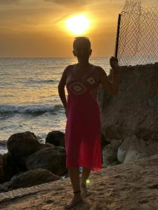 Chambre avec salle de bain privée في مبور: امرأة تقف على الشاطئ مع شبكة