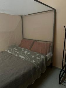 Chambre avec salle de bain privée في مبور: سرير مع مظلة في الغرفة