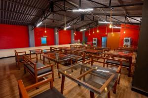 Zimmer mit Tischen, Stühlen und roten Wänden in der Unterkunft The Whistling Pine Woods in Varagampadi