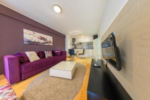 NAR Royalton Deluxe Apartment #40 في نيشْ: غرفة معيشة مع أريكة أرجوانية وتلفزيون