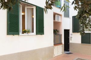 a white building with green shutters and a door at Appartamento Lentisco Centro by ElbaSummer in Marina di Campo +8 photos