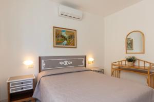 a bedroom with a bed and two tables and a mirror at Appartamento Lentisco Centro by ElbaSummer in Marina di Campo
