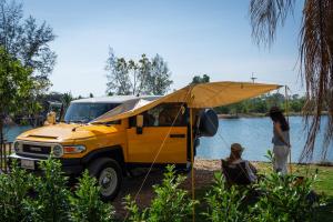 a woman standing next to a yellow truck with an umbrella at Camp Cayla - COASTA in Ban Ao Makham Pom