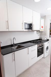 a white kitchen with a sink and a stove at GranVia Fira Apartment in Hospitalet de Llobregat
