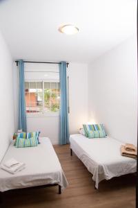 two beds in a room with blue curtains at GranVia Fira Apartment in Hospitalet de Llobregat