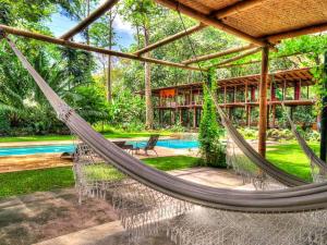 a hammock in front of a house with a pool at Iguana Lodge Beach Resort in Puerto Jiménez