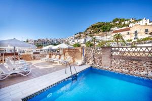 a swimming pool with lounge chairs and a resort at Hotel Villa Frigiliana in Frigiliana