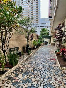 Un camino de piedra con bancos y árboles en un edificio. en Cozy, comfortable ocean view apartment for 4 people, en Santos