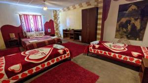 two beds in a room with red carpet at Rocky Mountain Hotel in Wadi Musa +5 photos