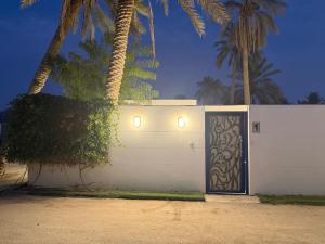 un garaje blanco con puerta y palmeras en رويال دايموند, en Al-Hasa