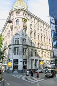 een groot gebouw met mensen die de straat ervoor oversteken bij Apartments Old City Center in Wenen
