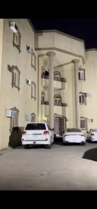 two white cars parked in front of a building at شقة ثلاثة غرف نوم وصالة in Al Baha