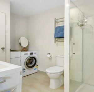 a bathroom with a toilet and a washing machine at Cozy Ensuite Room in Auckland