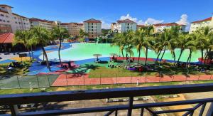 a large swimming pool with palm trees in a resort at Hasif Homestay Studio in Port Dickson