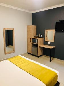 a room with a bed and a table and a mirror at Bayside Self Catering and Hotel 14 Monty Naicker Pinestreet Durban in Durban