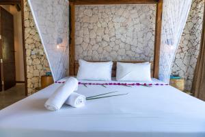 a bed with two rolled up towels on it at Natural Park Villa Resort in Pingwe