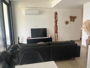 a living room with a black couch and a keyboard at Gem Waterfront Butterfly Appartement in Bijilo