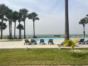 a pool with chairs and palm trees in a park at Gem Waterfront Butterfly Appartement in Bijilo