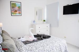 a room with a bed with a dresser and a tv at Batey Hotel Boutique in Boca Chica