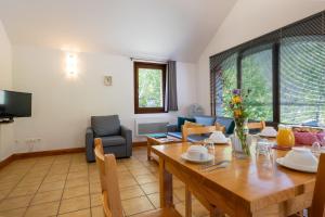 a living room with a wooden table and a dining room at Gîte Logement 4/6 personnes - Village de gites des Vignes in Les Vignes