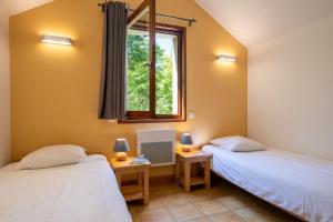 two beds in a room with a window at Gîte Logement 4/6 personnes - Village de gites des Vignes in Les Vignes