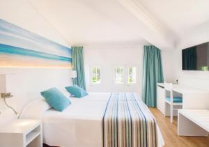 a bedroom with a white bed with blue pillows at Hotel Playas de Paguera in Paguera +86 photos