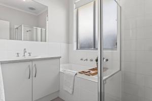 a white bathroom with a shower and a sink at Reef Retreat - Modern Beach House Sanctuary in Port Noarlunga +18 photos