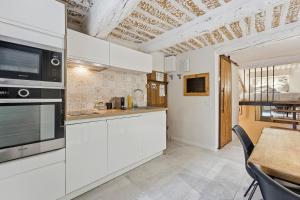 Una cocina con gabinetes blancos y una mesa de comedor. en Le Haut Castelet - Vieil Antibes, en Antibes
