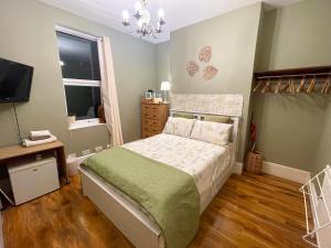 ein kleines Schlafzimmer mit einem Bett und einem Fernseher in der Unterkunft Victorian Rooms by Beach in Ramsgate