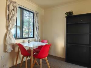 a dining room with a table and red chairs at Hearty Acres Farm Cottage in Auckland