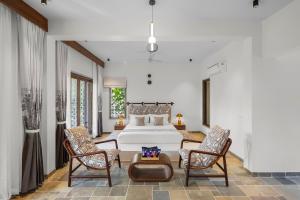 ein Schlafzimmer mit einem großen Bett und zwei Stühlen in der Unterkunft Viresco by Alaya Stays in Thūr