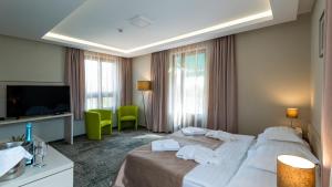 a hotel room with a bed and a television at Hotel Kamilla in Balmazújváros