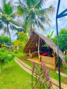 a hut with a thatched roof and palm trees at Udawalawe Safari House in Udawalawe +74 photos